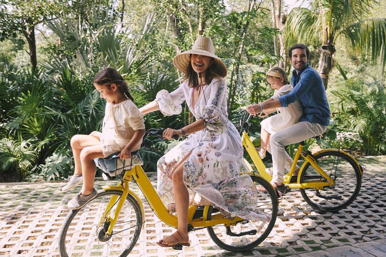 Paola Sáez de Montagut con su familia en bicicleta entre la vegetación de Tulum